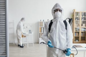 Dwie osoby w strojach ochronnych przeprowadzają dezynfekcję mieszkania w Krakowie