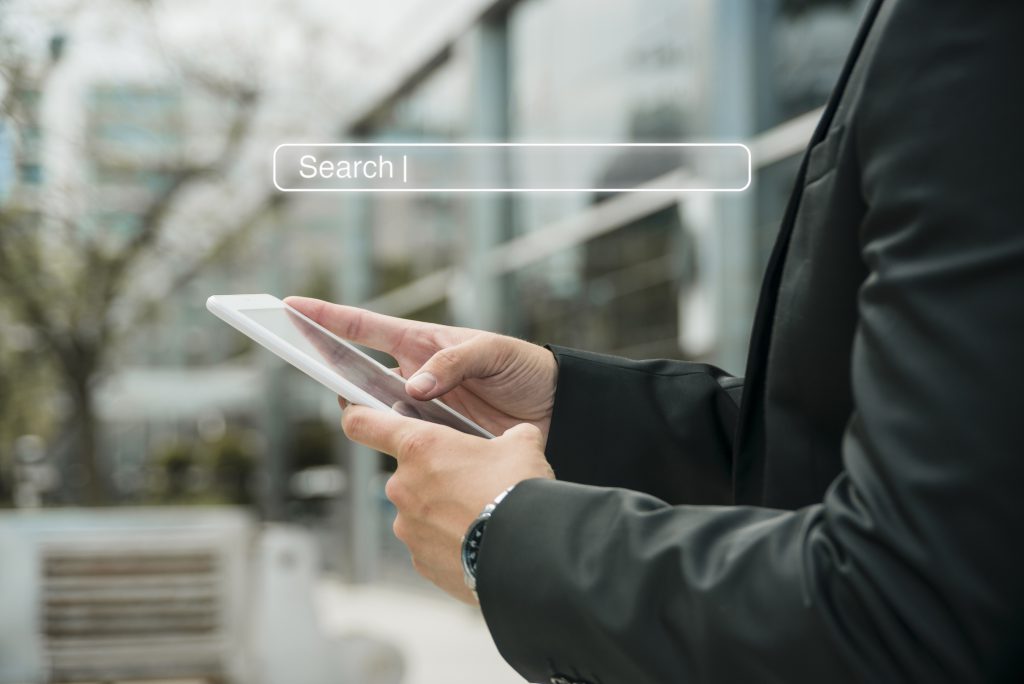 Dłonie mężczyzny trzymające telefon i wyszukujące informacje na Google Maps wskazujące na działanie marketingu lokalnego.