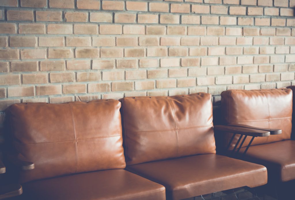 Eleganckie meble skórzane Oświęcim w odcieniu brązu, doskonale komponujące się z industrialną ceglaną ścianą – połączenie stylu i jakości.