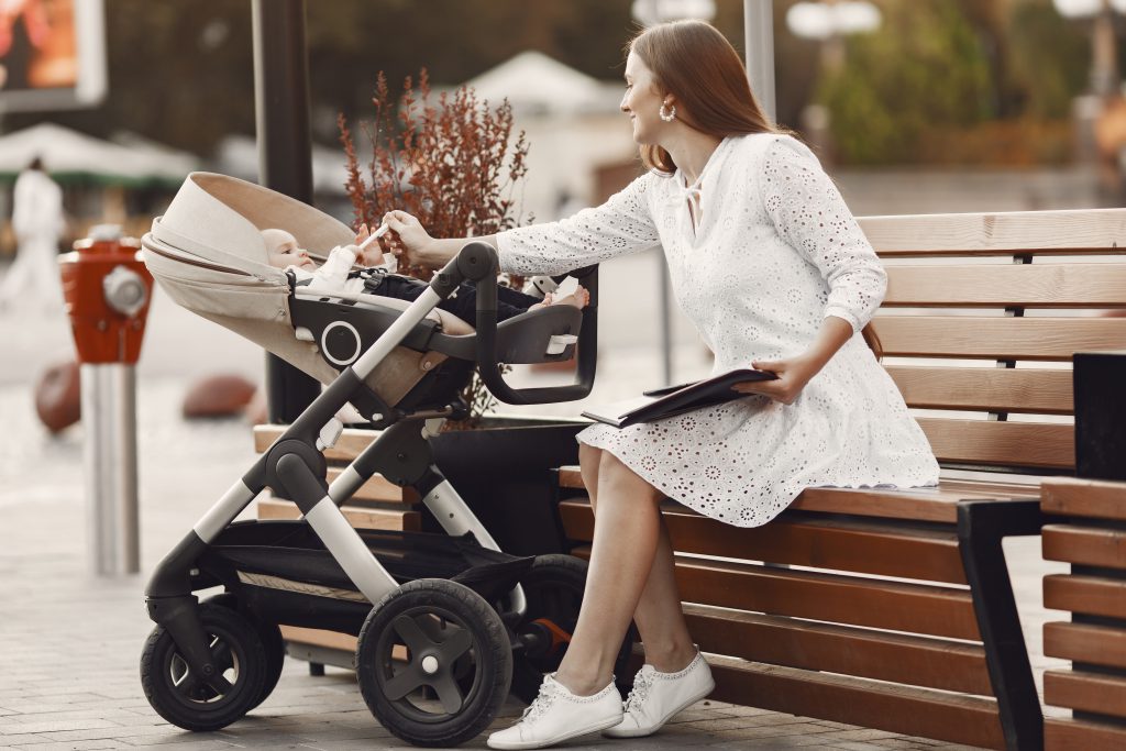 Mama karmiąca niemowlę w eleganckim wózku – wózek spacerowy z gondolą na miejskie spacery