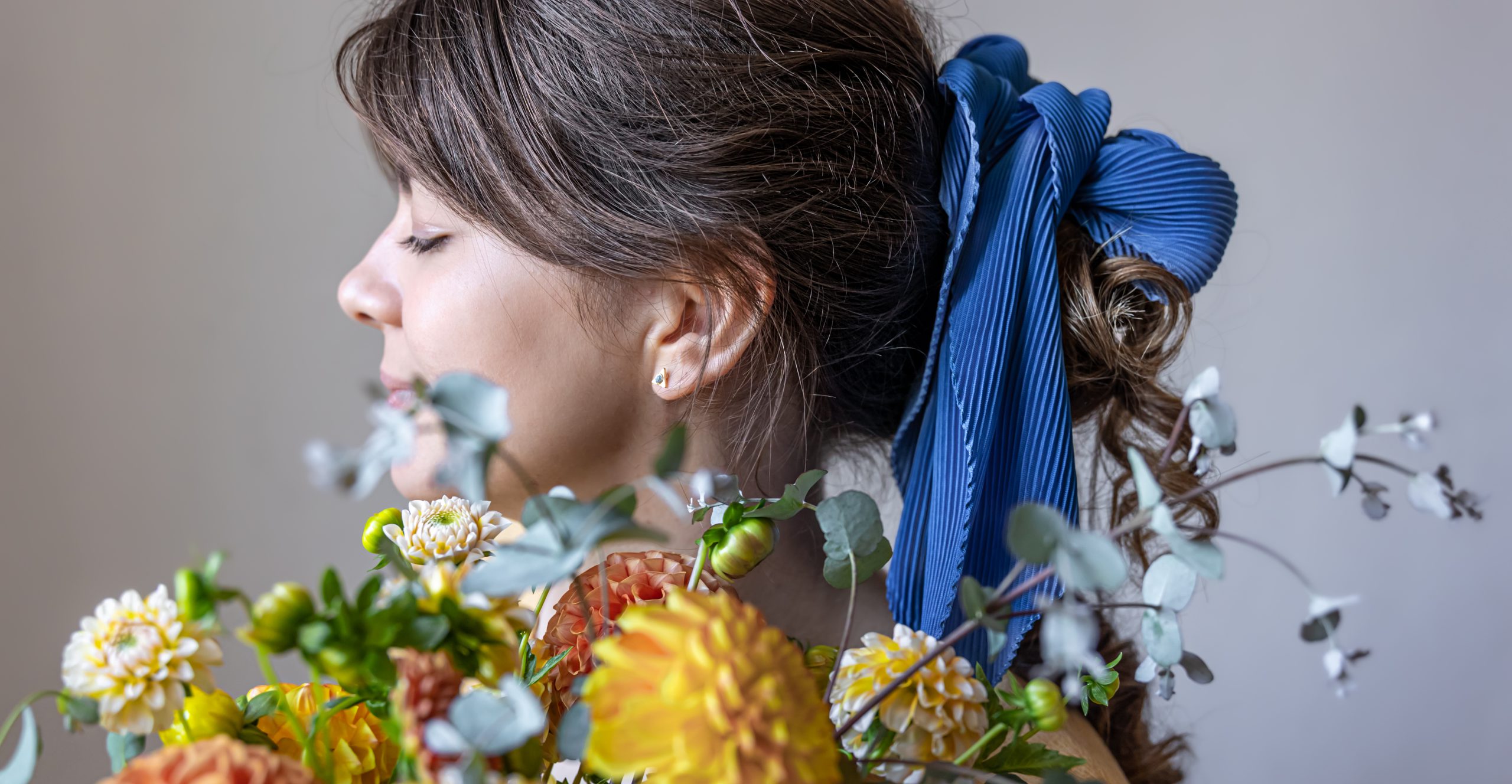 Kobieta trzymająca bukiet chryzantem z kokardą na włosach, w tradycyjnej fryzurze, z widoczną gumką z kokardą