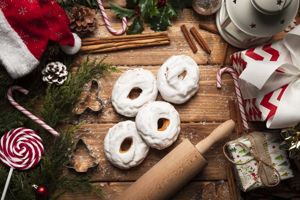 Świąteczna kompozycja przedstawiająca słodycze na święta, lukrowane pierniki, laski cukrowe i dekoracje bożonarodzeniowe na drewnianym tle.