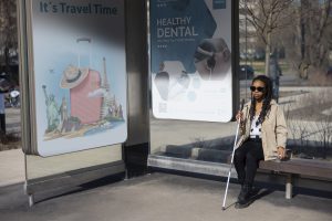 Banery reklamowe Warszawa na przystanku autobusowym obok kobiety siedzącej z laską