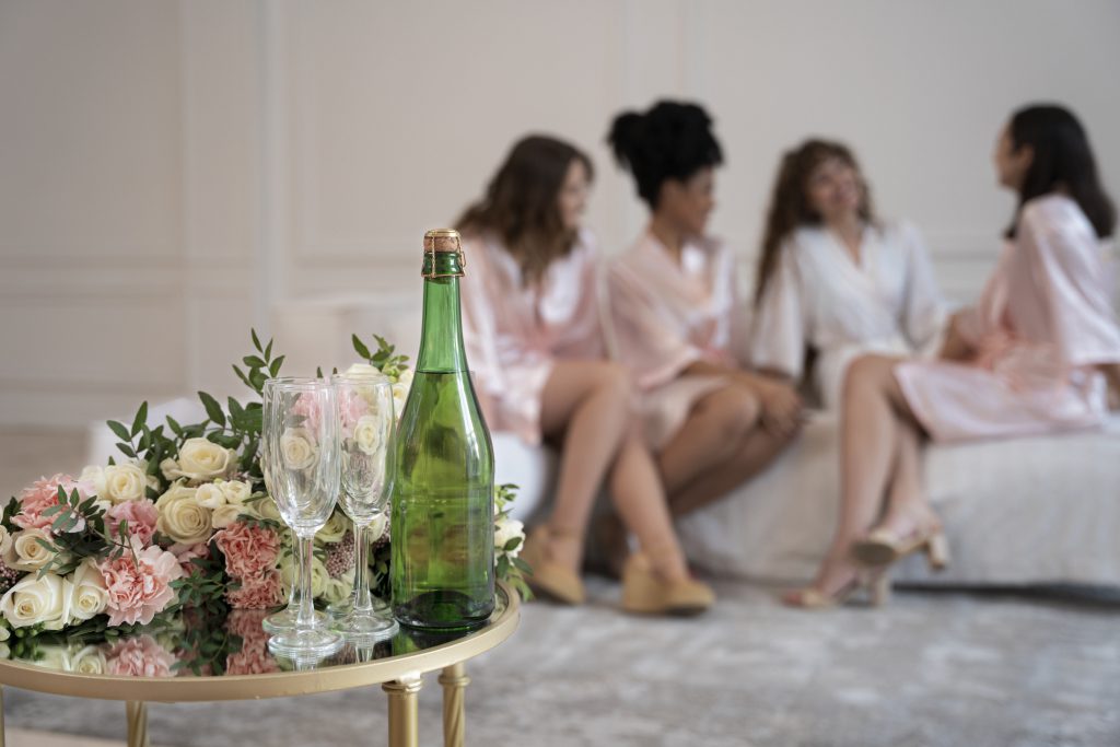 Grupa kobiet w szlafrokach podczas przygotowań, celebrująca wieczór panieński Kraków przy kwiatach i winie.