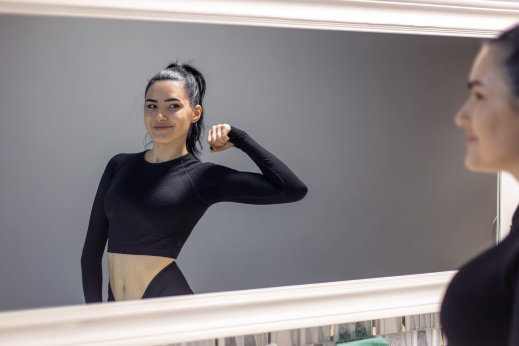 Kobieta ćwicząca przed nowoczesnym lustrem – lustra na zamówienie do siłowni i domowych wnętrz