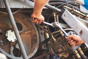 Mechanik wykonujący serwis maszyn drogowych podczas naprawy układu hydraulicznego