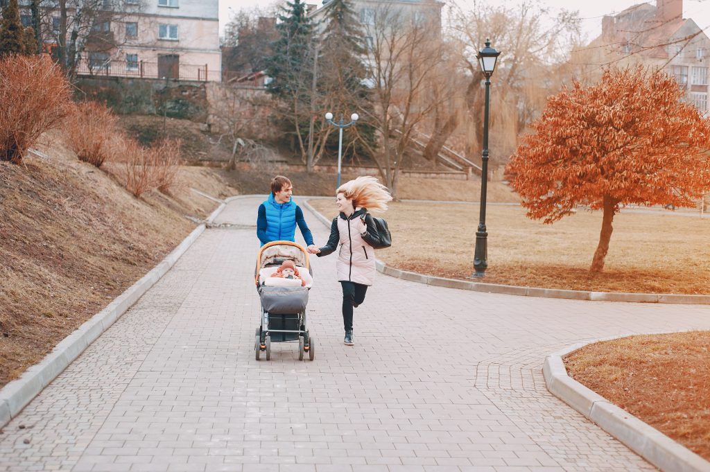 Rodzice na spacerze z dzieckiem w nowoczesnym wózku – polskie wózki dziecięce w miejskim parku
