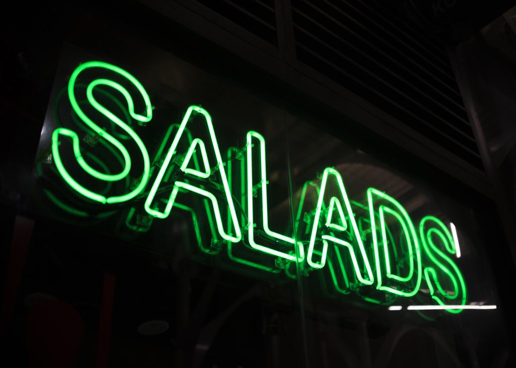 Podświetlane logo na ścianę w formie zielonego neonu z napisem SALADS