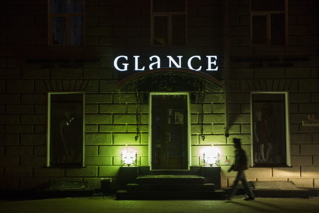 Podświetlane logo na ścianę nad wejściem do lokalu nocą, tworzące efektowną iluminację budynku.