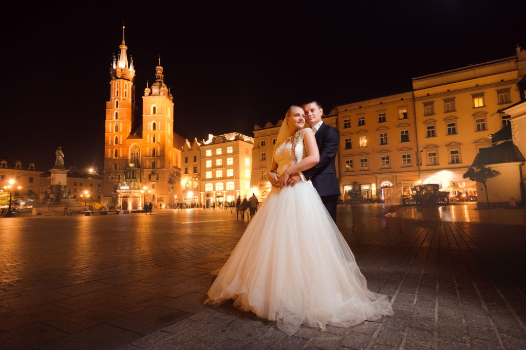 przytulająca się młoda para podczas sesji na tle kościoła mariackiego świętująca wesele w krakowie