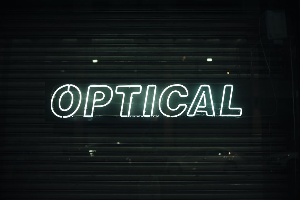 Podświetlane logo na ścianę w formie białego neonu z napisem OPTICAL
